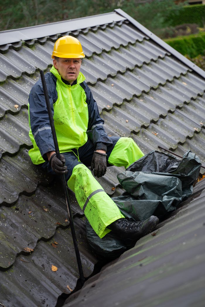 Home A construction worker in safety gear performing roof maintenance outdoors.