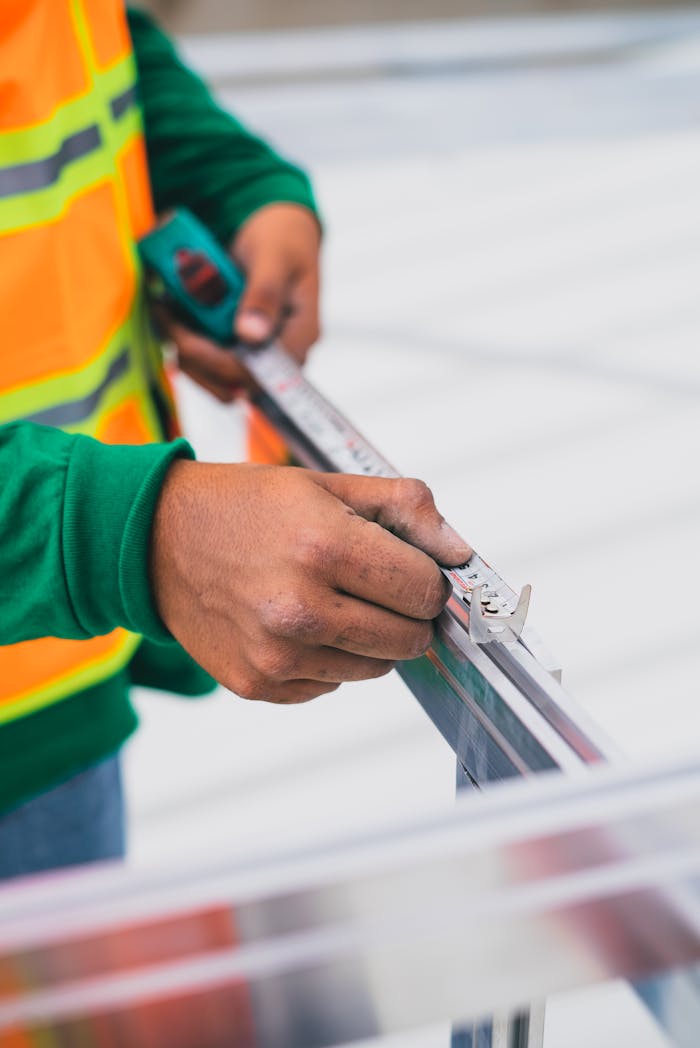 Close-up of worker's hands using measuring tape on a construction site.